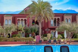 a red building with a palm tree and a swimming pool at Delta Hotels by Marriott Marrakech Eden Andalou in Marrakesh