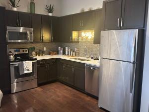 uma cozinha com armários pretos e um frigorífico de aço inoxidável em On The Go Stays(Penthouse) em Dallas