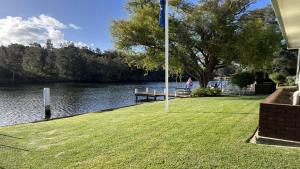 a flag pole in the grass next to a body of water at A Slice Of Paradise in Sussex Inlet +14 photos
