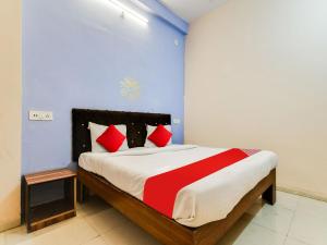 OYO Hotel Airport View في إندوري: غرفة نوم بسرير كبير ومخدات حمراء