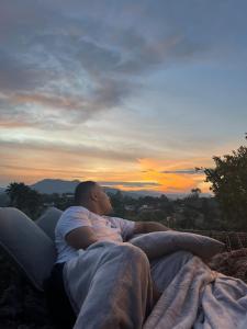 a man laying on a couch watching the sunset at Glamping Carmen de Viboral in Carmen de Viboral