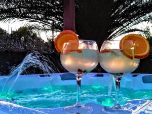 two glasses with orange slices on a table next to a swimming pool at Caloura Earth Accommodation in Caloura