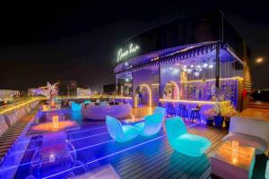 清邁的住宿－Moose Hotel Nimman，屋顶酒吧在晚上提供蓝色的椅子和桌子