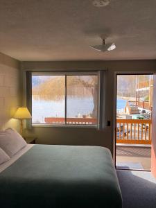 a bedroom with a bed and a large window with a view at Sun Beach Motel in Osoyoos