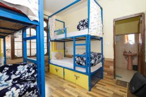a bunk bed room with two bunk beds and a bathroom at One More Night hostel and community living in McLeod Ganj