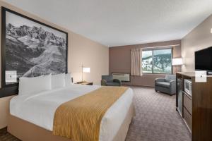 a hotel room with a bed and a flat screen tv at Super 8 by Wyndham Sturgis in Sturgis