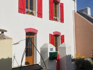 ein weißes Gebäude mit roten Fenstern und roten Fensterläden in der Unterkunft Maison Locmaria, 4 pièces, 6 personnes - FR-1-418-245 in Locmaria