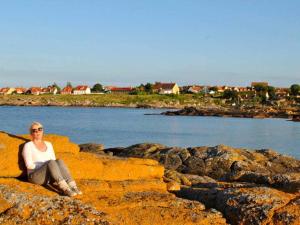 una mujer sentada en unas rocas cerca del agua en 6 person holiday home in Svaneke en Svaneke
