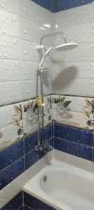 um chuveiro numa casa de banho com azulejos azuis e brancos em غرفه بشقه بأطلاله على البحر em ‘Izbat al Qaşr