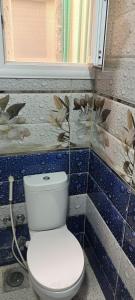 a bathroom with a toilet in a blue tiled wall at غرفه بشقه بأطلاله على البحر in ‘Izbat al Qaşr