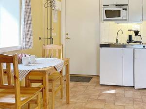 een keuken met een tafel en stoelen en een keuken met witte apparatuur bij 3 person holiday home in SKIVARP in Skivarp