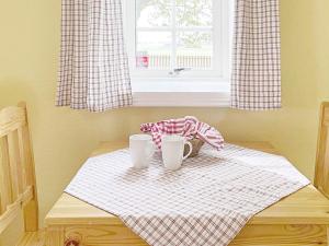een tafel met twee kopjes en een mand op een handdoek bij 3 person holiday home in SKIVARP in Skivarp