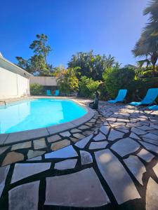 una piscina con sillas y un patio de piedra. en Kaz Ô Flambloyant avec piscine privative, proche Grand'Anse, en Petite Île