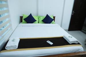 a bed with a remote control sitting on top of it at AIRPORT COCHIN ROYAL RESIDENCY in Ernakulam