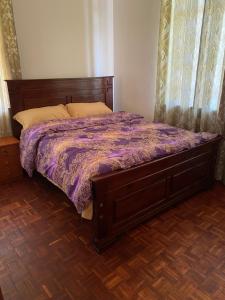 - un lit avec une couette violette dans une chambre dans l'établissement Sigona Serene Valley, à Nairobi