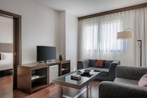 AC Hotel Bologna by Marriott في بولونيا: غرفة معيشة مع أريكة وتلفزيون