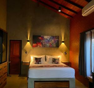 1 dormitorio con 1 cama con una pintura en la pared en Negombo Morawala Beach Villa en Negombo