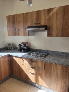 a kitchen with wooden cabinets and a stove top oven at Bel appartement au cœur de Hay Ryad in Rabat