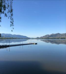 a lake with a dock and mountains in the background at Sun Beach Motel in Osoyoos
