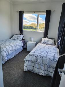 Oasis Rural Retreat في Norsewood: سريرين في غرفة نوم مع نافذة