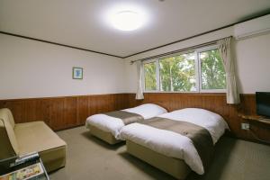 1 dormitorio con 2 camas y ventana en Pension Ashitaya, en Furano