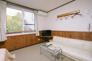 a living room with a white couch and a tv at Pension Ashitaya in Furano