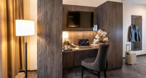 ein Zimmer mit einem Schreibtisch, einem Stuhl und einem Fernseher in der Unterkunft PLAZA INN Mannheim in Mannheim