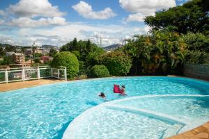 Dos personas en una piscina con una silla. en Jardin d'Ivandry Piscine et terrasse, en Antananarivo