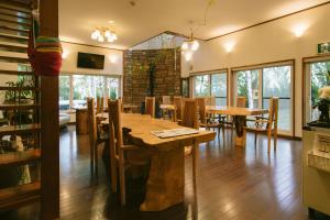 a dining room with a wooden table and chairs at Pension Ashitaya in Furano