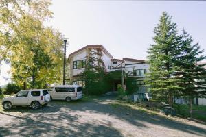 a house with two cars parked in front of it at Pension Ashitaya in Furano