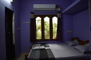 een blauwe slaapkamer met een bed en een raam bij Rainbow Guest House in Tiruvannamalai
