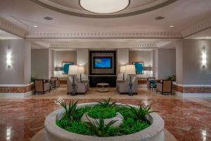 a lobby with a waiting area with chairs and a fountain at Sheraton Suites Fort Lauderdale at Cypress Creek in Fort Lauderdale