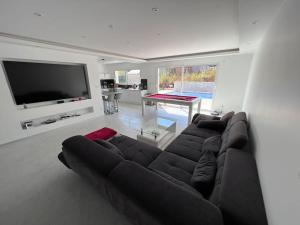 a living room with a large couch and a flat screen tv at Magnifique Villa avec piscine in Corcelles-les-Monts