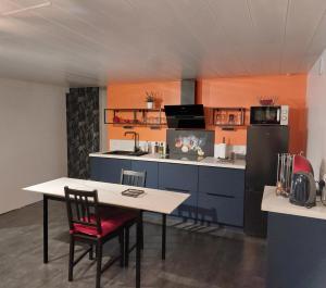 a kitchen with a table and a refrigerator at Comme dans un écrin - T2 de 50 m² avec jardin, terrasse et piscine in Vernaison