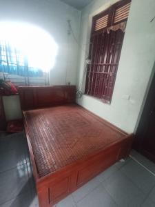 a wooden bed in a room with a window at Nhà Nghỉ Minh Đức in Kim Côn