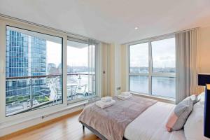 Schlafzimmer mit einem großen Fenster mit Blick auf das Wasser in der Unterkunft Lovely 2BD flat with River view in London