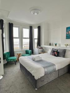 a bedroom with a large bed and two green chairs at Wns Southend -on-Sea in Southend-on-Sea