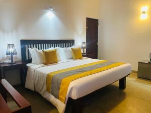 1 dormitorio con 1 cama grande con almohadas amarillas en THE Mangrove cave Hotel en Balapitiya