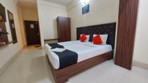 a bedroom with a large bed with red pillows at Hotel Tripletree Bhubaneswar in Bhubaneshwar
