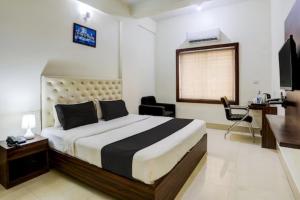 um quarto com uma cama, uma secretária e uma televisão em Hotel Tripletree Bhubaneswar em Bhubaneshwar