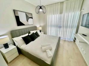 ein Schlafzimmer mit einem großen Bett mit weißen und schwarzen Kissen in der Unterkunft Luxury Golf View Penthouse - Pool+Gym+Beach+Fishing in Punta Cana
