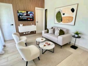 ein Wohnzimmer mit einem Sofa, Stühlen und einem Waschbecken in der Unterkunft Luxury Golf View Penthouse - Pool+Gym+Beach+Fishing in Punta Cana