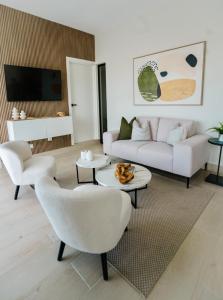 ein Wohnzimmer mit einem weißen Sofa und Stühlen in der Unterkunft Luxury Golf View Penthouse - Pool+Gym+Beach+Fishing in Punta Cana