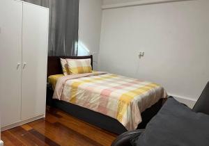 a small bedroom with a bed with a striped blanket at Comfortable Studio+free parking for small car in Sydney