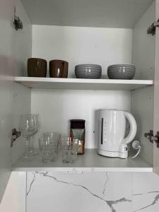 a kitchen shelf with plates and glasses and a microwave at Comfortable Studio+free parking for small car in Sydney