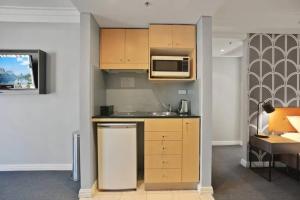 une cuisine avec des armoires en bois et un micro-ondes dans l'établissement KozyGuru | Sydney CBD | Amazing 2 Bed Family Apt, à Sydney