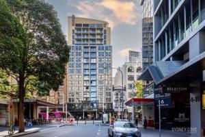 une rue urbaine avec de grands bâtiments et une voiture dans la rue dans l'établissement KozyGuru | Sydney CBD | Amazing 2 Bed Family Apt, à Sydney