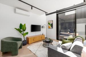 een woonkamer met een bank en een tv bij Fitzroy North Apartments by Urban Rest in Melbourne
