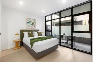 een slaapkamer met een groot bed en een tafel bij Fitzroy North Apartments by Urban Rest in Melbourne