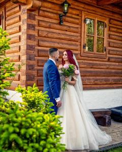 a bride and groom standing in front of a cabin at Liptovská Drevenica in Liptovský Mikuláš